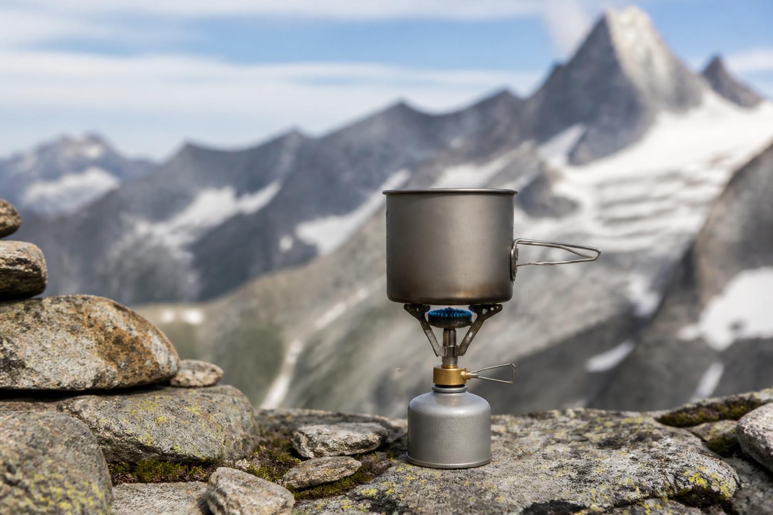 Réchaud à gaz compact sur terrain alpin rocheux avec montagnes en arrière-plan