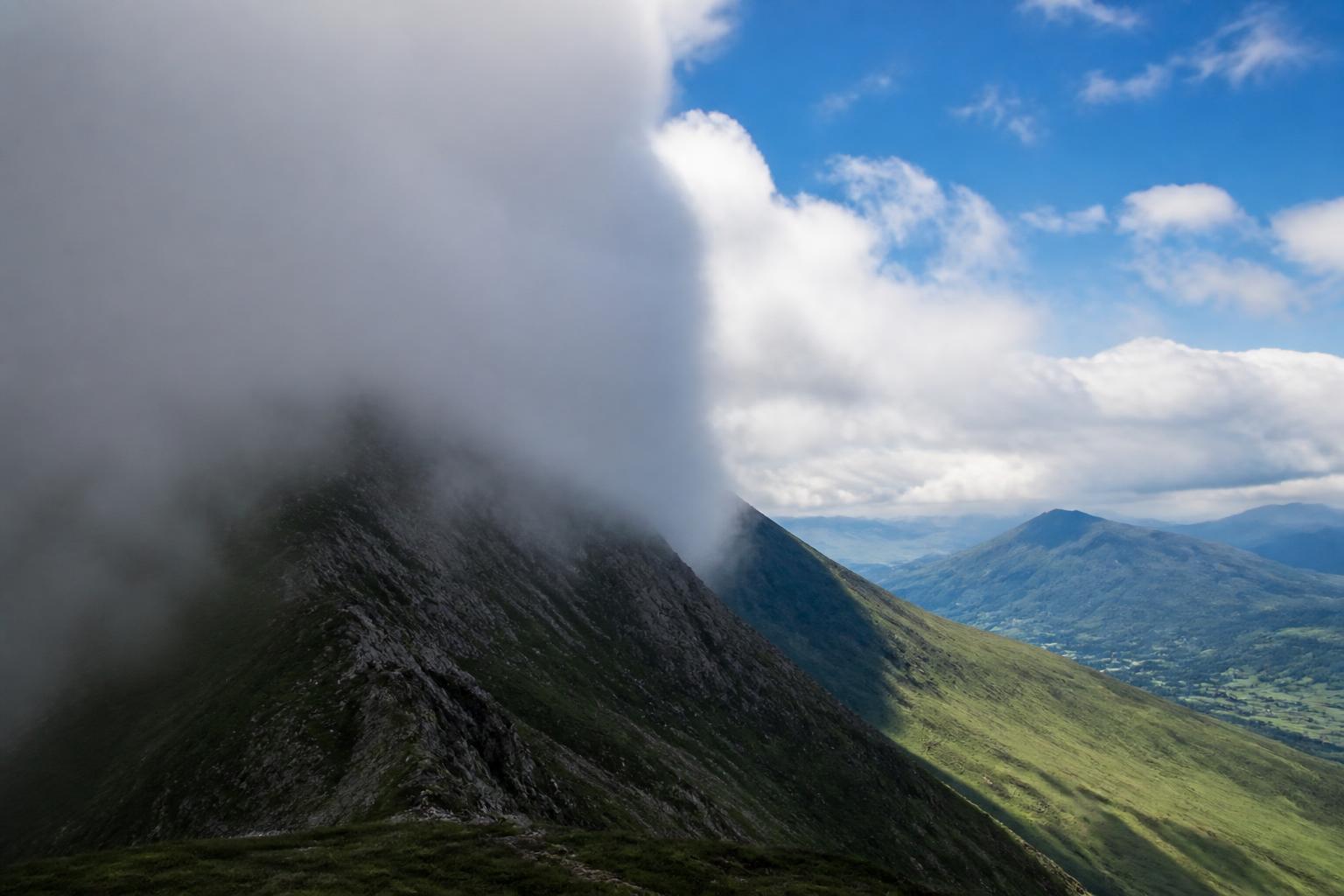 Deux versants opposés d'une même crête : celui au vent bouché par les nuages, celui sous le vent dégagé et ensoleillé