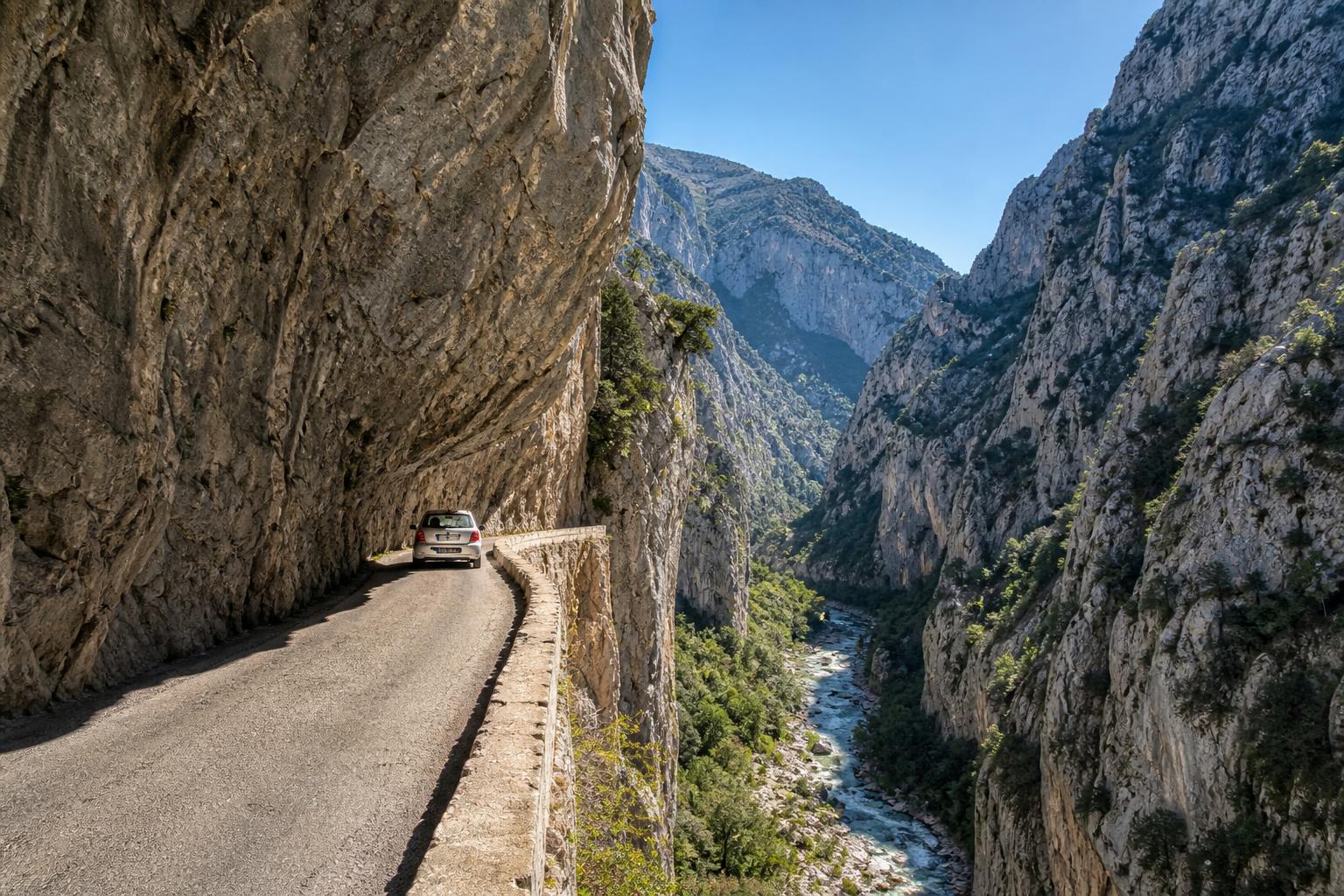 La route étroite taillée dans la falaise calcaire des gorges de Galamus, un véhicule s'y engage prudemment