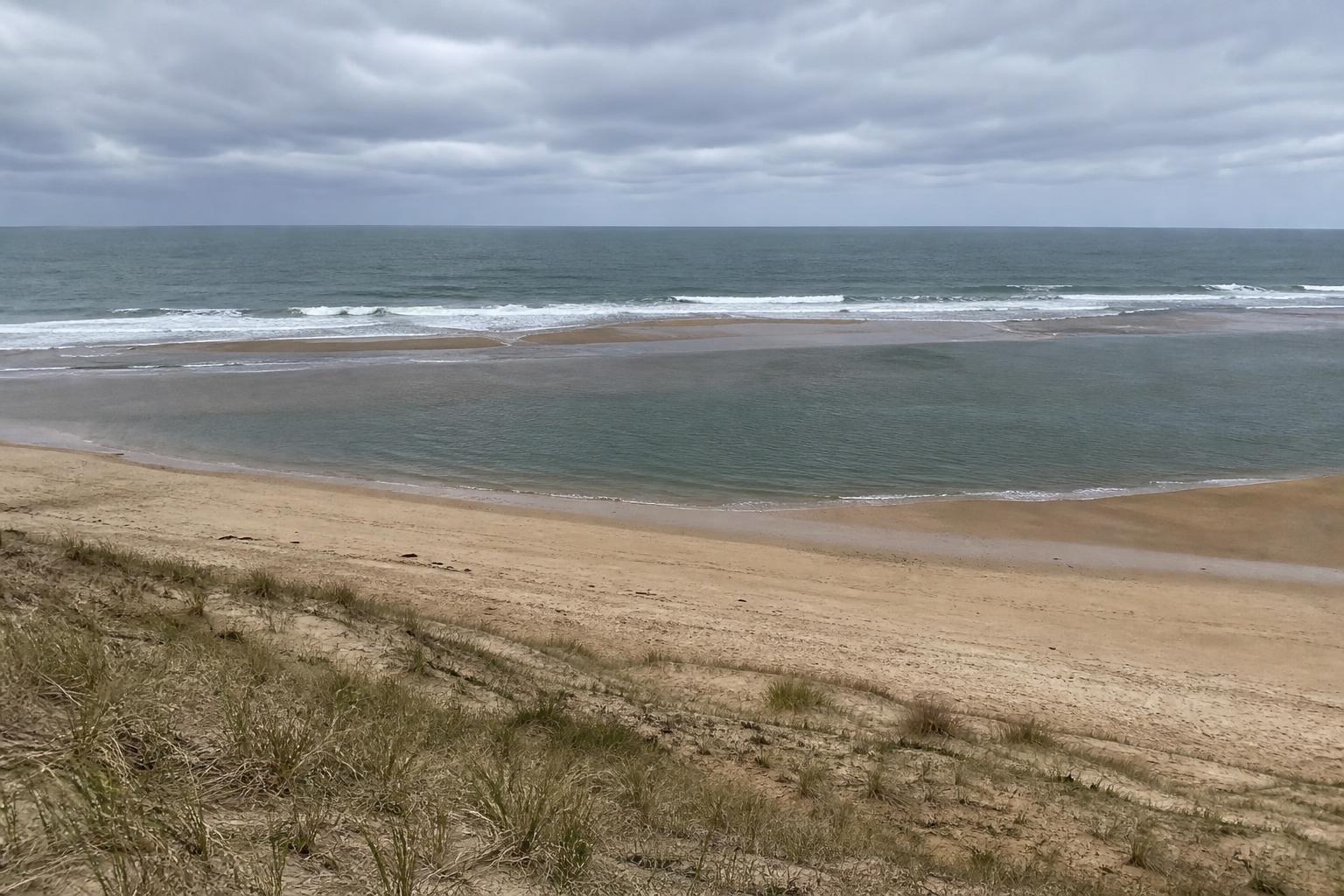 Vue d'une plage atlantique à marée basse montrant une baïne, un banc de sable au large et les zones de déferlement